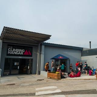 A group of people gathered on the outside area for a BBQ, in the late afternoon sun.